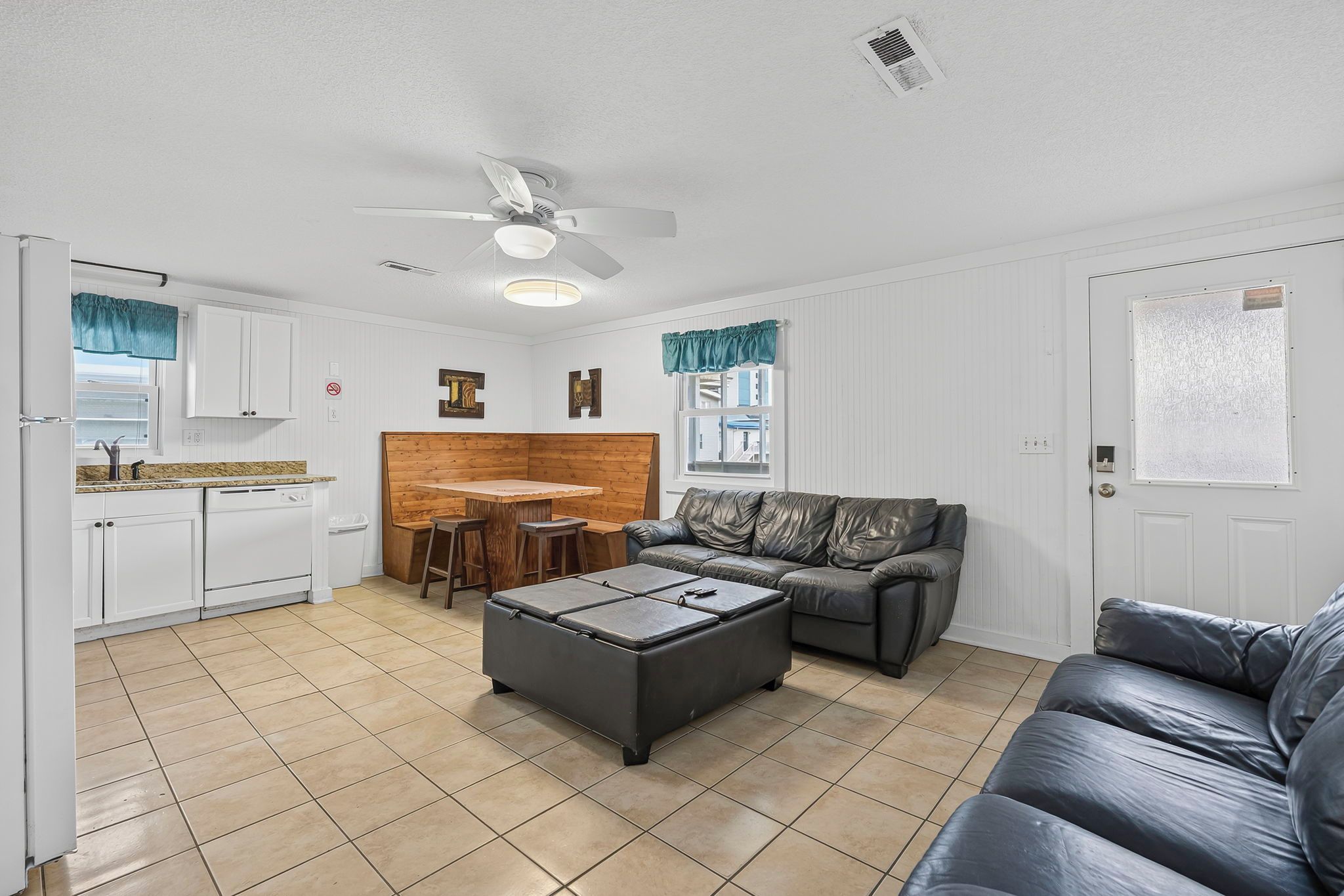 A compact living space with a kitchenette, a dining area, a sofa, and a coffee table.