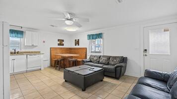 A compact living space with a kitchenette, a dining area, a sofa, and a coffee table.