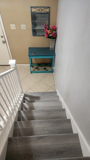 A staircase with a white railing, a teal console table with a vase of flowers, and a wall-mounted mirror. - Luxury and spacious 4-bedroom house in adorable San Antonio with AC (San Antonio)