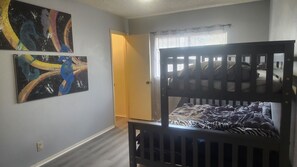 A room with a bunk bed, two abstract paintings, a door, and a window with blinds. - Luxury and spacious 4-bedroom house in adorable San Antonio with AC (San Antonio)