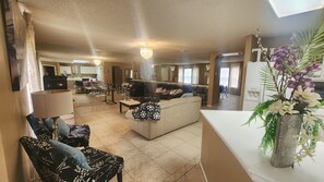 A spacious living area with a sofa, chairs, a dining table, and a kitchen in the background. - Luxury and spacious 4-bedroom house in adorable San Antonio with AC (San Antonio)