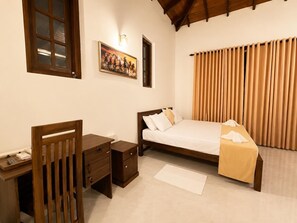 A bedroom with a bed, a desk, a chair, a nightstand, and a painting on the wall.
