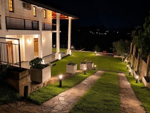Un espace extérieur bien éclairé, doté d’un chemin pavé, de jardinières et d’un bâtiment avec de nombreuses fenêtres et un balcon.