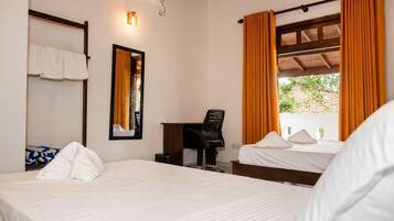 A hotel room with a bed, a desk, a chair, a mirror, and a window with curtains.