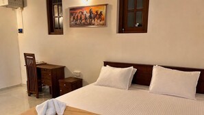 A hotel room with a large bed, a wooden desk, a chair, and a painting on the wall. - Luxury 5BR Family Villa Near Airport, Pool, Rooftop, Sleeps 14+ (Pansilgoda)