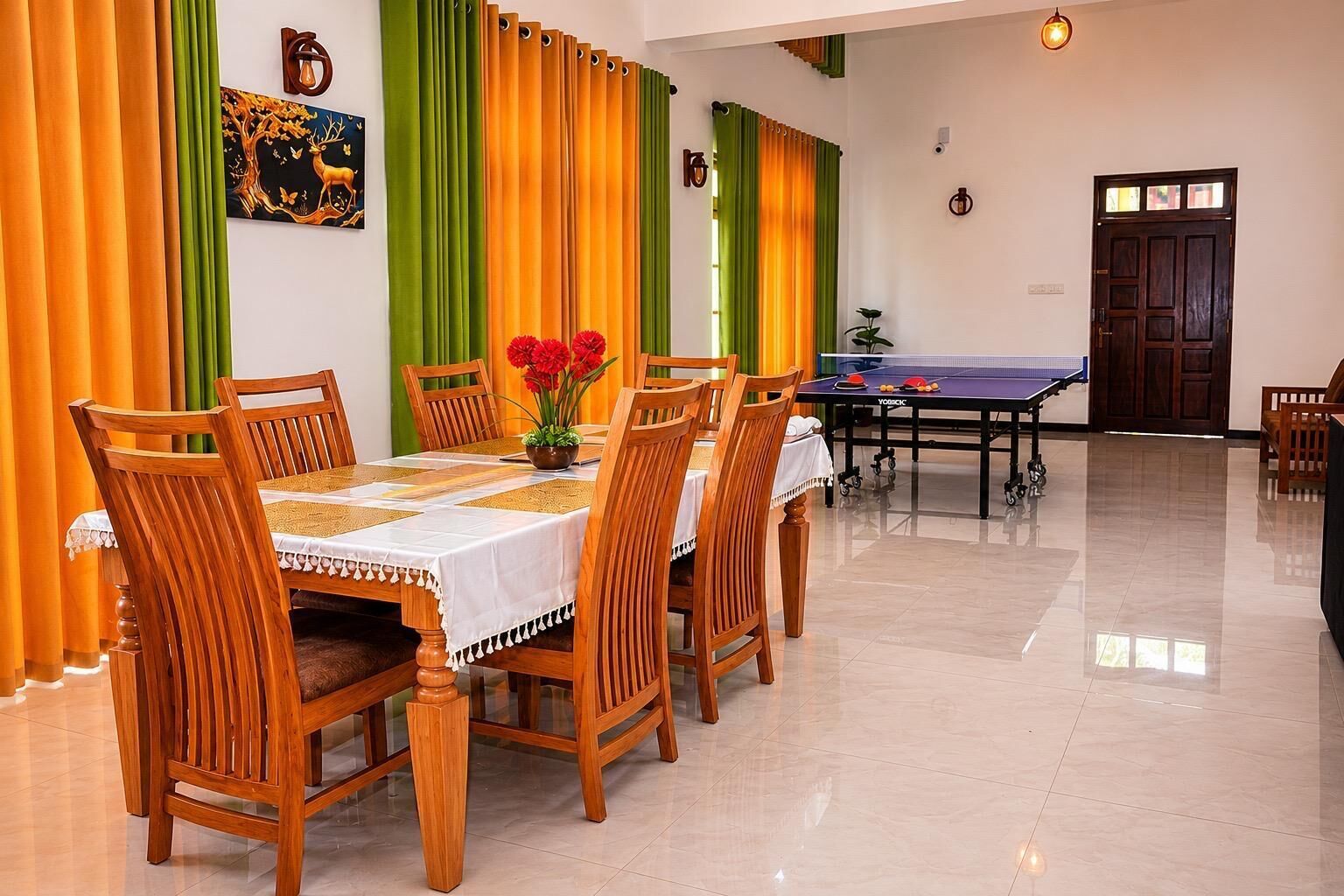A dining area with a table set for six, chairs, a ping pong table, and a wall with a painting.