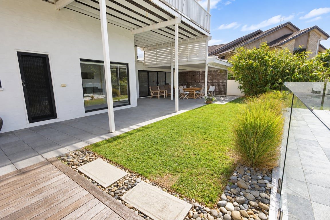 A modern house with a covered patio, a well-maintained lawn, and a stone pathway leading to the entrance.