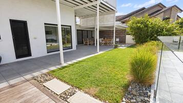 A modern house with a covered patio, a well-maintained lawn, and a stone pathway leading to the entrance.