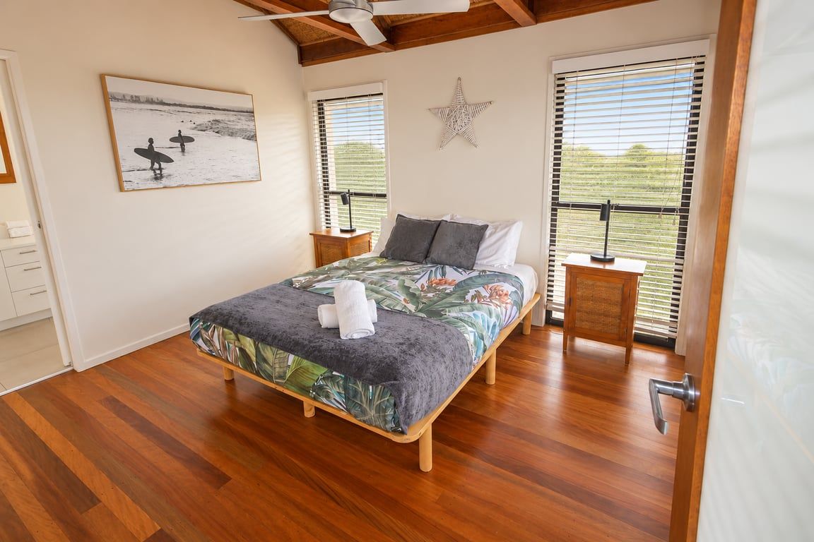 Une chambre à coucher avec un lit, des tables de chevet, une décoration en forme d’étoile et une fenêtre avec des stores.