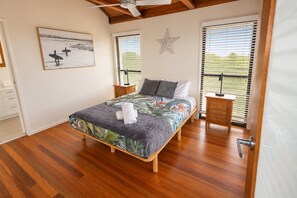 A bedroom with a bed, nightstands, a star decoration, and a window with blinds. - Sea Breezes and Sand Between Your Toes (Sunshine Coast)