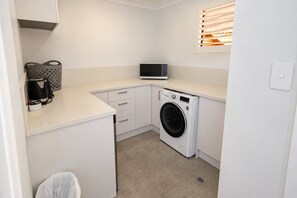 A compact laundry room with a washing machine, a microwave, and a coffee maker.