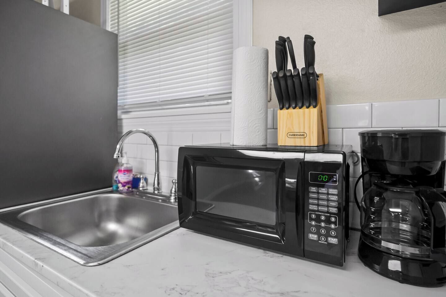 A kitchen with a microwave, coffee maker, and a knife block.