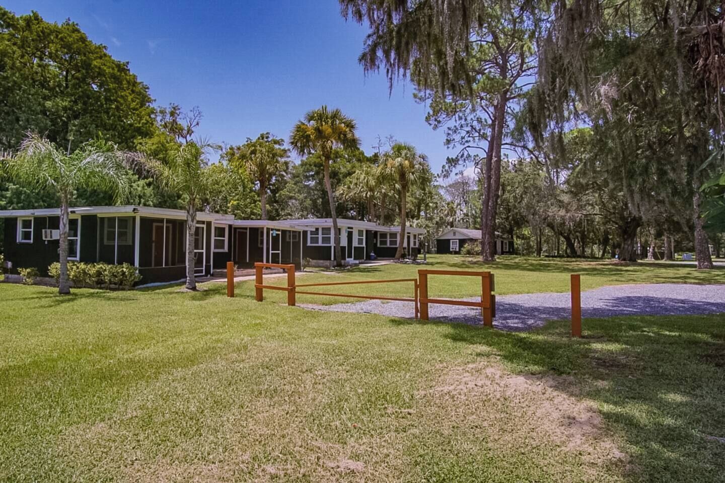 A row of single-story buildings with large windows, surrounded by a well-maintained grassy area and trees.