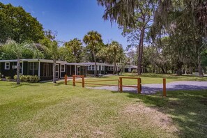 A row of single-story buildings with large windows, surrounded by a well-maintained grassy area and trees.