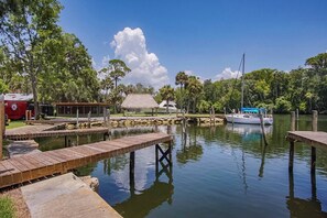 A calm water body with wooden docks, a boat, and a thatched-roof structure.