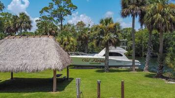 A yacht docked at a marina with a thatched structure nearby.