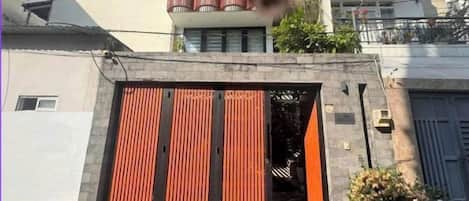 Um edifício residencial com portão fechado, varanda e vasos de plantas.
