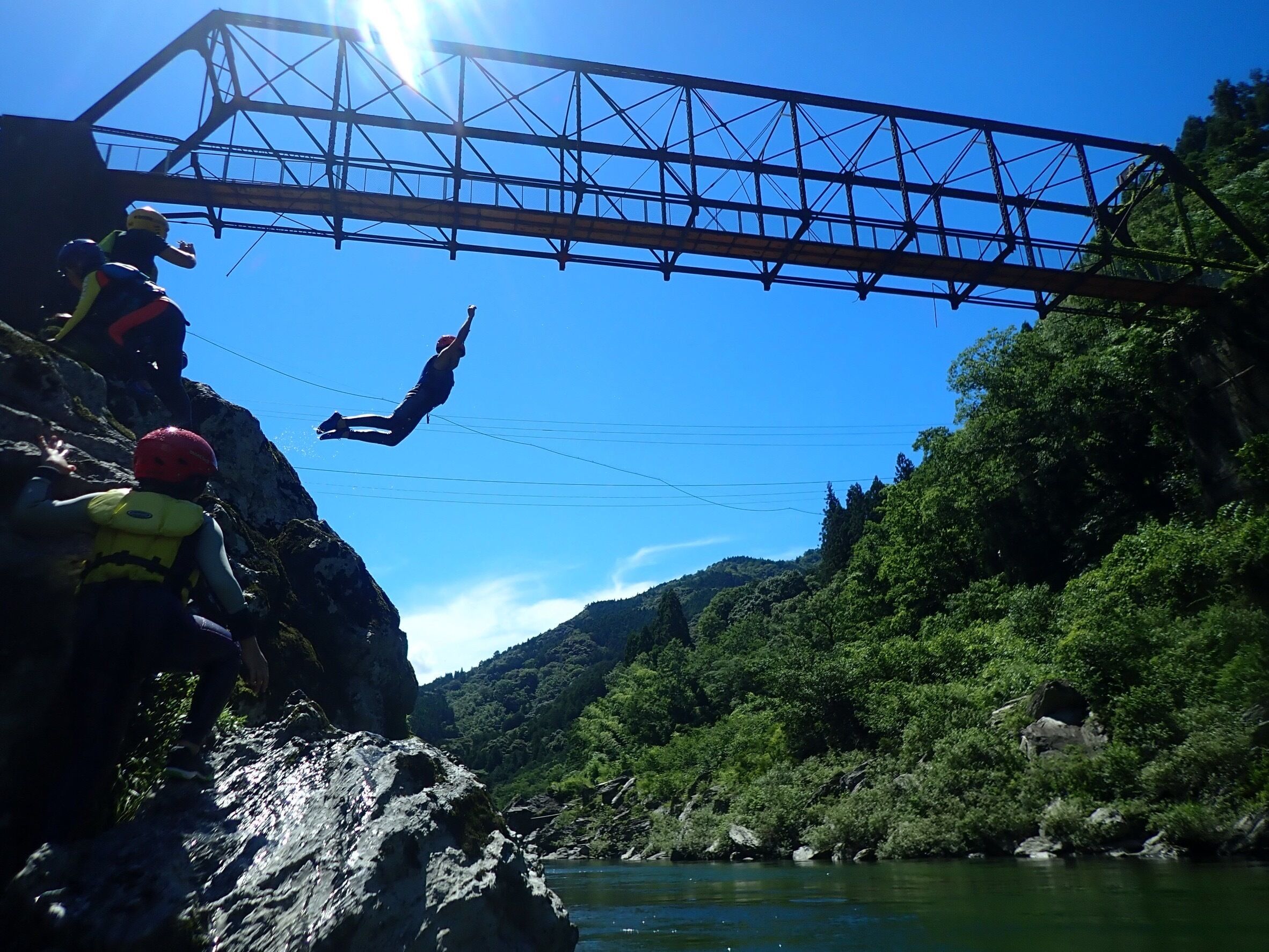 A bridge with a person bungee jumping off it.