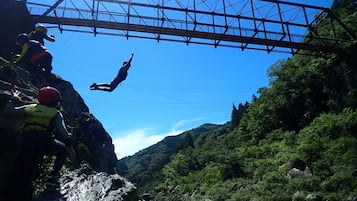 A bridge with a person bungee jumping off it.