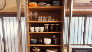 Una cocina con armarios abiertos que exhiben diferentes platos y utensilios de cocina.