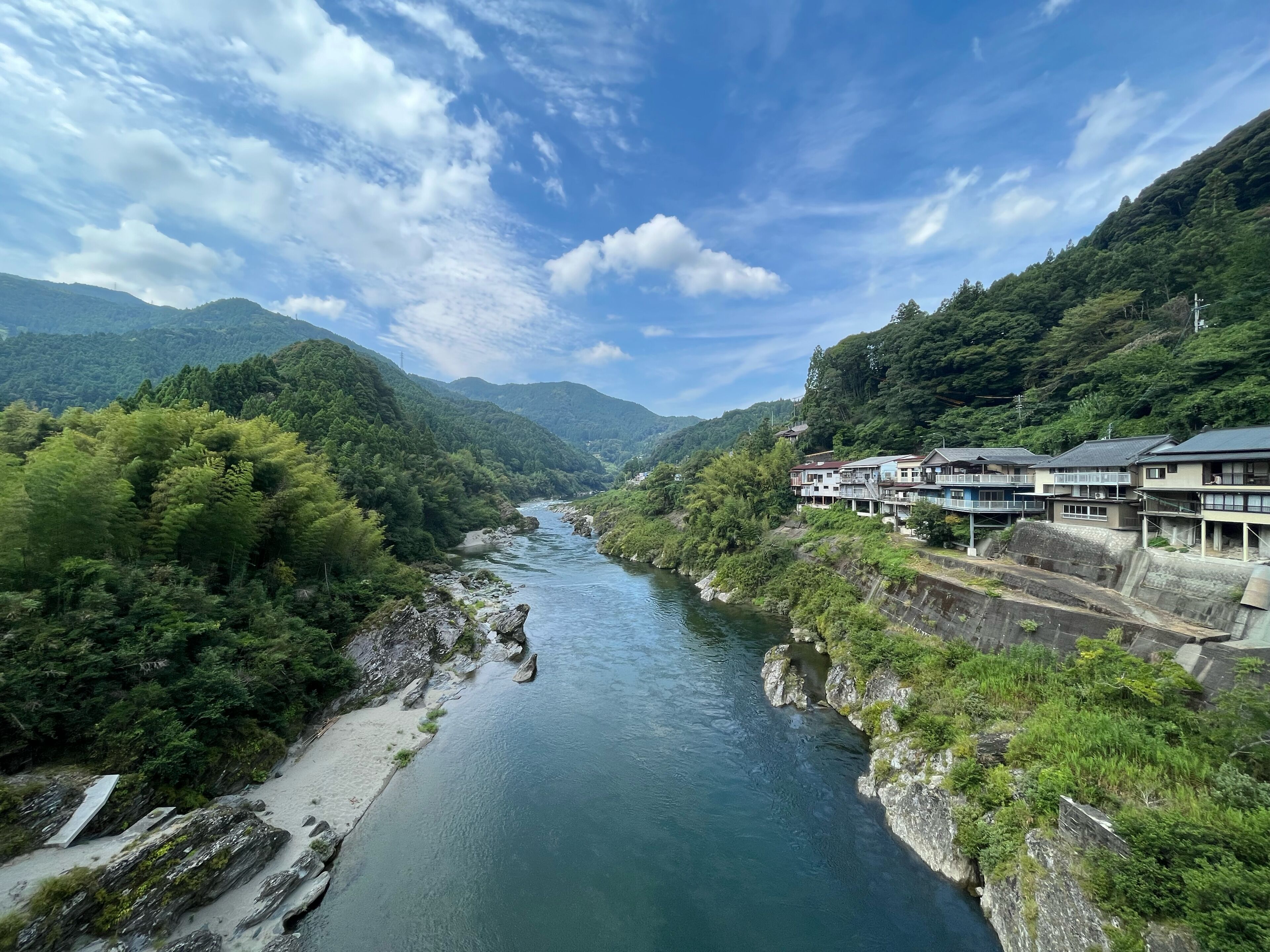 A river flowing through a valley with houses on stilts along the riverbank.