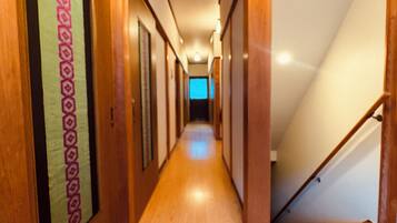 A wooden hallway with a staircase on the right, leading to an upper floor.