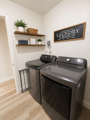 Une buanderie équipée d’un lave-linge, d’un sèche-linge et d’une pancarte au-dessus du sèche-linge.