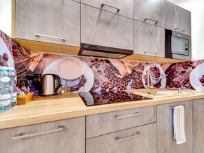 Eine moderne Küche mit einer Kaffeemotiv-Spritzschutzwand, Edelstahlgeräten und Holzschränken.