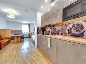 Une cuisine moderne avec des meubles en bois, un four à micro-ondes et un revêtement mural décoré sur le thème du café.