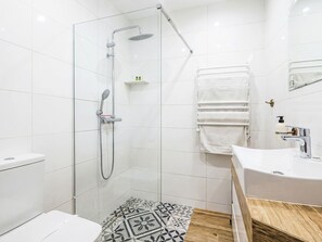 Une salle de bain moderne avec une douche à parois de verre, un lavabo blanc et un carrelage décoratif.