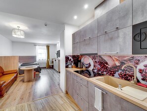 Eine moderne Küche mit grauen Schränken, einer Holz Arbeitsplatte und einer Spritzschutzleiste mit Kaffeemotiv.