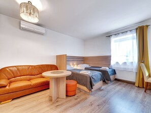 A modern hotel room with a leather sofa, two single beds, a small round table, and a window with curtains. - Apartament nr 31 by Interhome (Gliwice)