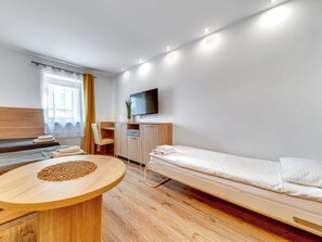 A modern hotel room with a bed, a desk, a chair, a TV, and a window with curtains. - Apartament nr 31 by Interhome (Gliwice)