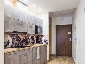 A modern kitchen with grey cabinets, a microwave, and a coffee-themed backsplash. - Apartament nr 31 by Interhome (Gliwice)