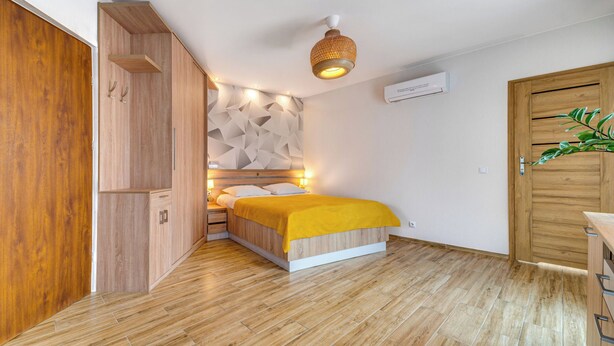 Una camera da letto con un letto, un armadio in legno e un condizionatore d'aria a parete.