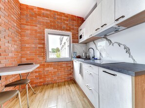 A kitchen with a brick wall, a window, a sink, and cabinets. - Apartament nr 24 by Interhome (Gliwice)