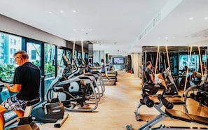 Un gimnasio moderno con cintas de correr, elípticas y máquinas de pesas.