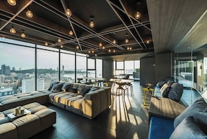 A spacious living area with a large sofa, a dining table, and a view of the cityscape through large windows. - Sea View 2 Bed Room Excellent Location (Pattaya)