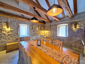 Un comedor rústico con una mesa de madera, sillas y un camino de mesa estampado.