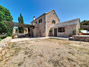 Una casa de piedra con porche cubierto y patio de grava.