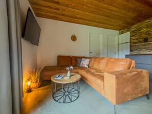 A modern living room with a sofa, a coffee table, and a TV mounted on the wall.