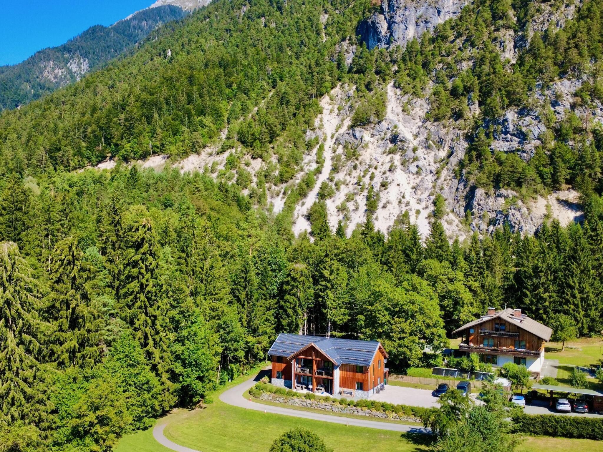 A lodge with a modern design, surrounded by dense forest and mountains.