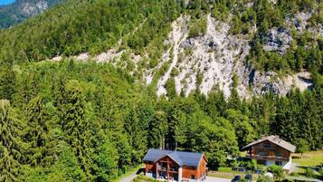 A lodge with a modern design, surrounded by dense forest and mountains.