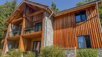 A two-story wooden house with a balcony and stone foundation.