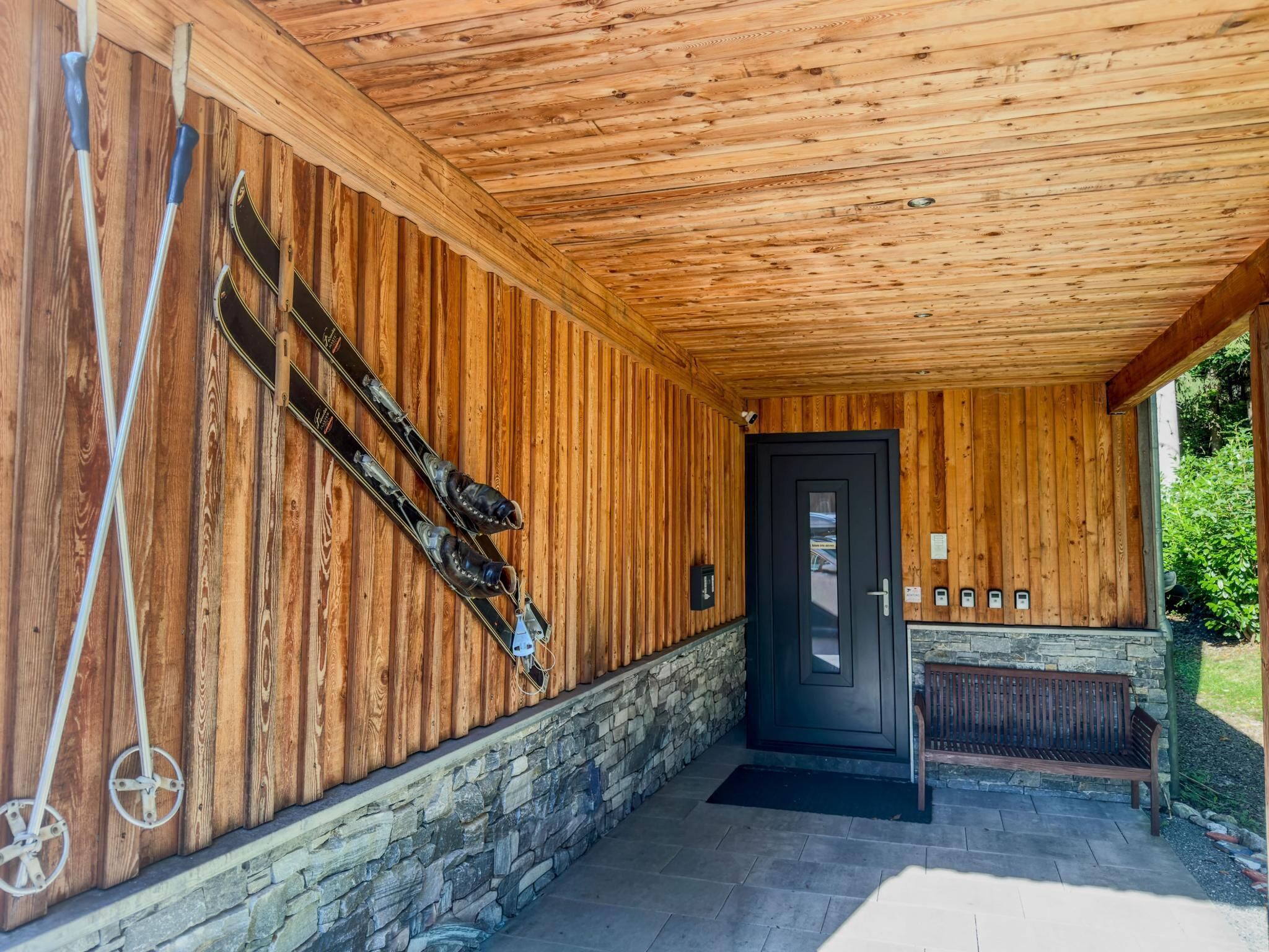 A wooden exterior with a stone base, a black door, and a bench outside.