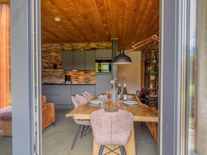 Ein stilvoller Essbereich mit Holztisch, Stühlen und einer Küche im Hintergrund.