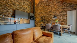 Et moderne interiør med en stenvæg, en lædersofa og et spiseområde med stole og et bord.