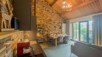 A modern kitchen with a stone wall, a dining area with a table and chairs, and a large window with a view.