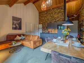 A modern living room with a sofa, coffee table, and dining table set for a meal. - Cozy holiday apartment by a lake in Carinthia (Hermagor-Pressegger See)