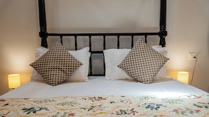 A bed with a floral-patterned bedspread, two pillows with a geometric pattern, and a black headboard. - Casa Particular in Cansaulim, India (Arossim)